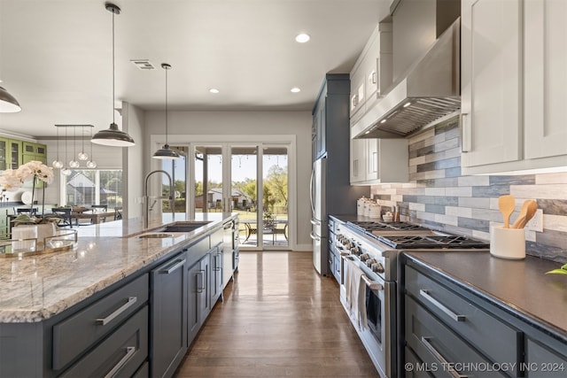 kitchen featuring sink, wall chimney exhaust hood, dark hardwood / wood-style flooring, decorative light fixtures, and appliances with stainless steel finishes