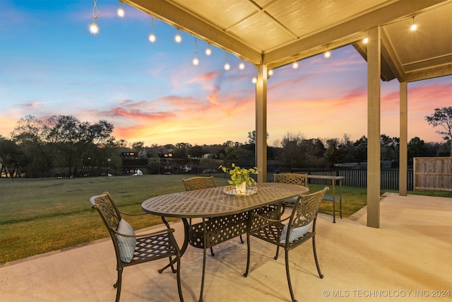 patio terrace at dusk featuring a lawn