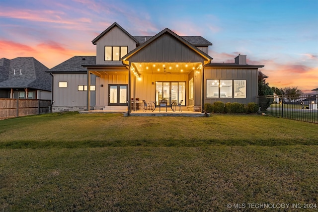 back house at dusk featuring a yard, french doors, and a patio