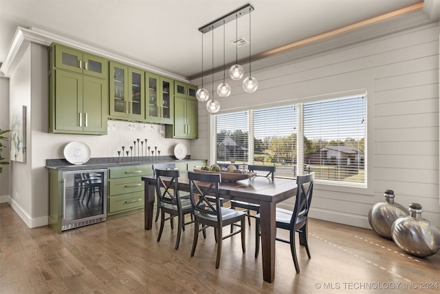 dining space featuring dark hardwood / wood-style floors, crown molding, beverage cooler, and wooden walls