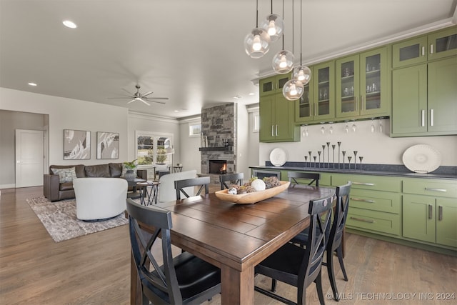 dining space with ceiling fan, dark hardwood / wood-style flooring, ornamental molding, and a fireplace