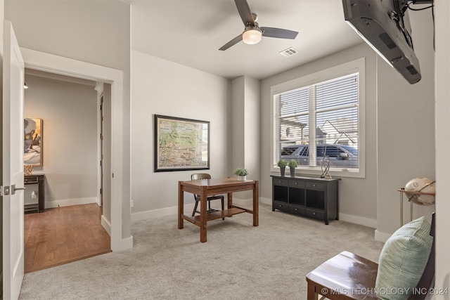 carpeted office space with ceiling fan