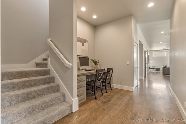 staircase with hardwood / wood-style floors and built in desk