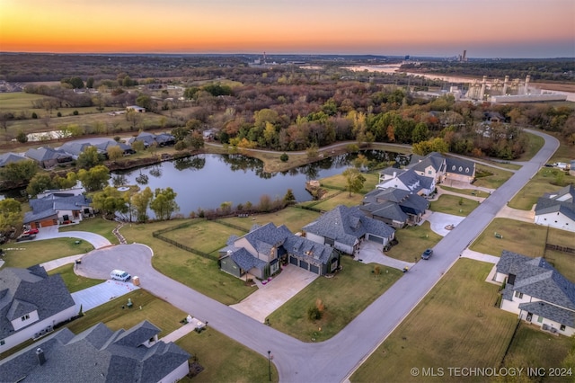 aerial view at dusk featuring a water view