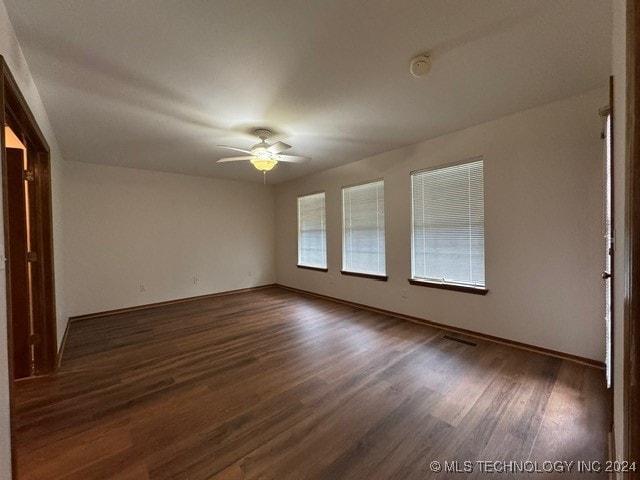 spare room with dark hardwood / wood-style flooring and ceiling fan