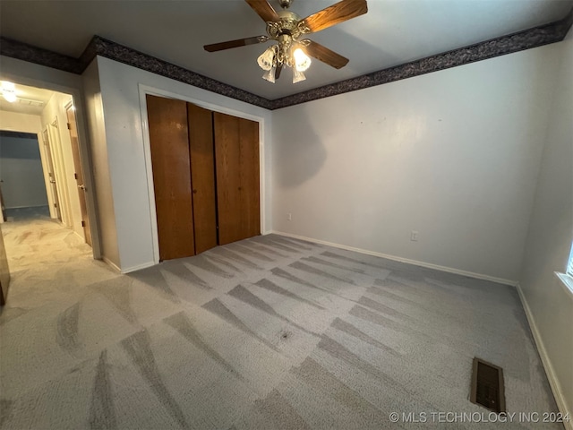 unfurnished bedroom with light carpet, ceiling fan, and a closet