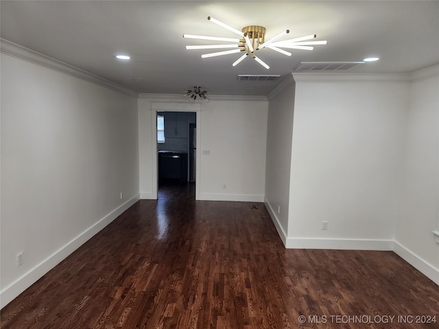 empty room featuring dark hardwood / wood-style floors, an inviting chandelier, and ornamental molding