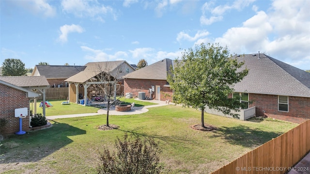 view of front facade featuring central air condition unit, an outdoor fire pit, and a front lawn