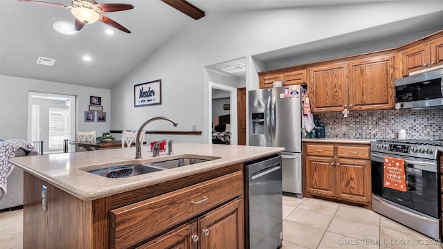 kitchen featuring appliances with stainless steel finishes, tasteful backsplash, a kitchen island with sink, sink, and beam ceiling