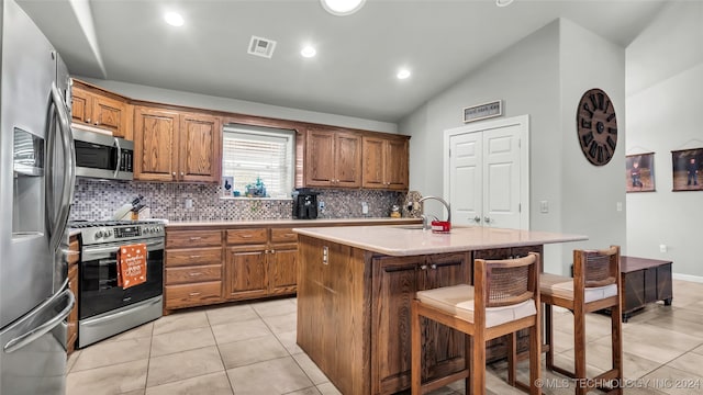 kitchen with sink, a kitchen breakfast bar, lofted ceiling, a kitchen island with sink, and appliances with stainless steel finishes