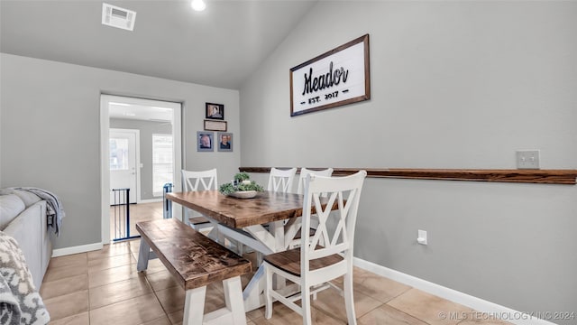 dining space with light tile patterned floors and vaulted ceiling