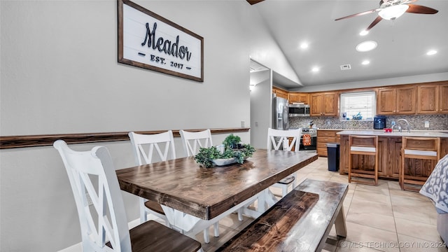 tiled dining room featuring ceiling fan, lofted ceiling, and sink