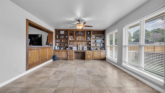 bar featuring ceiling fan, built in desk, and light tile patterned floors