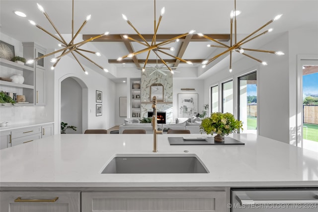 kitchen featuring a center island with sink, sink, stainless steel dishwasher, white cabinets, and a high end fireplace