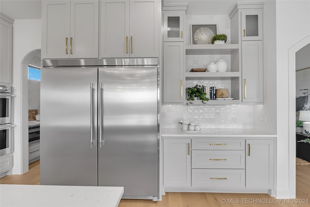 kitchen with stainless steel appliances, light wood-type flooring, and backsplash