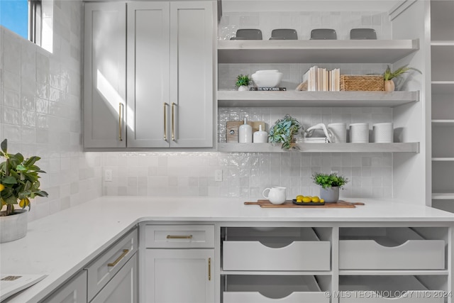 interior space featuring gray cabinets, tasteful backsplash, and light stone countertops