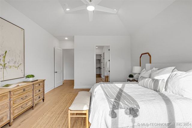 bedroom featuring lofted ceiling, ceiling fan, light wood-type flooring, and a walk in closet