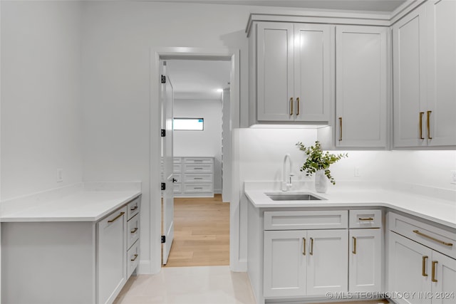 kitchen with light wood-type flooring, gray cabinets, and sink