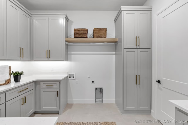 laundry room featuring cabinets, hookup for a washing machine, light tile patterned floors, and electric dryer hookup