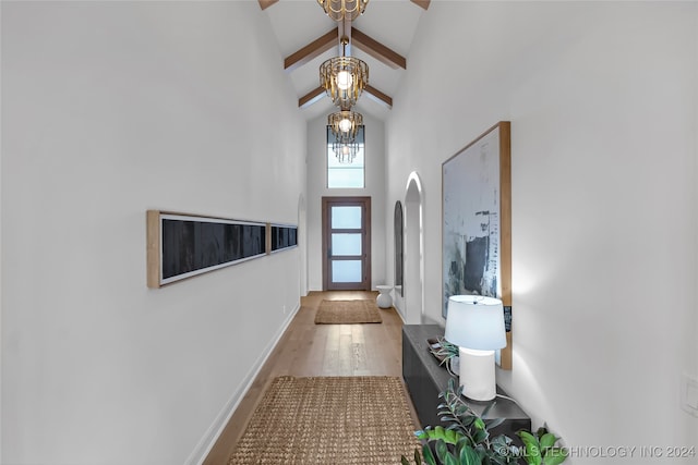 foyer featuring hardwood / wood-style floors, beamed ceiling, an inviting chandelier, and high vaulted ceiling