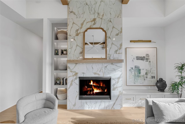 living room with built in shelves, a premium fireplace, and hardwood / wood-style flooring