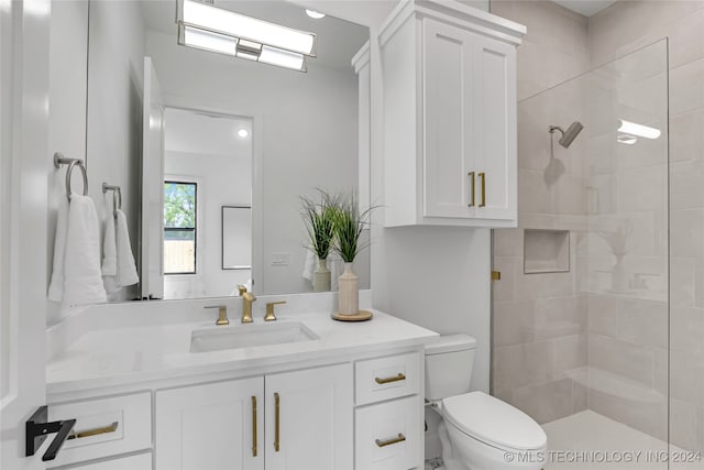 bathroom featuring toilet, vanity, and a tile shower