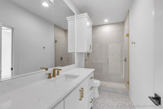 bathroom featuring toilet, vanity, and a shower with door