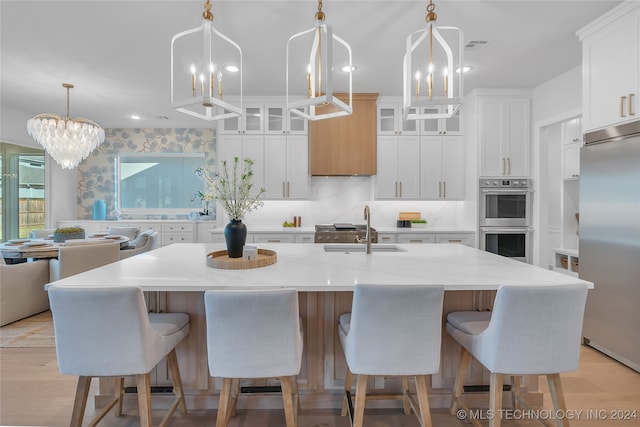 kitchen featuring stainless steel appliances, white cabinetry, and a kitchen island with sink