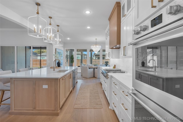 kitchen with a spacious island, white cabinetry, sink, and hanging light fixtures