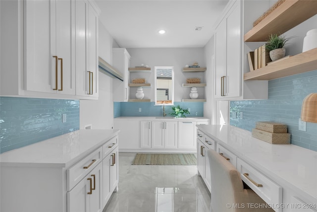 kitchen featuring white cabinets, decorative backsplash, sink, and light stone counters