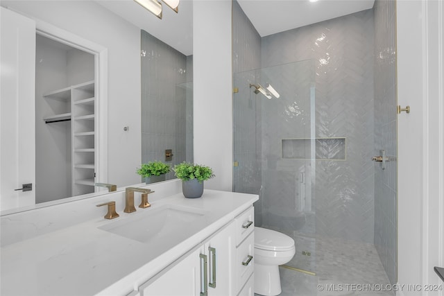 bathroom with tiled shower, toilet, and vanity