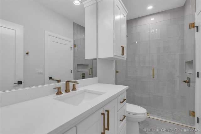 bathroom featuring toilet, vanity, and a shower with shower door