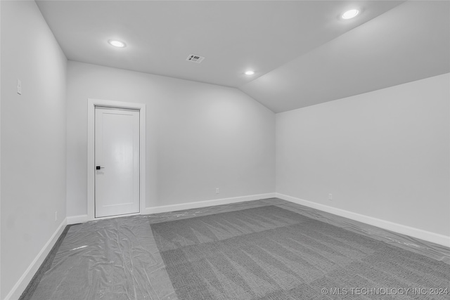 carpeted spare room featuring lofted ceiling