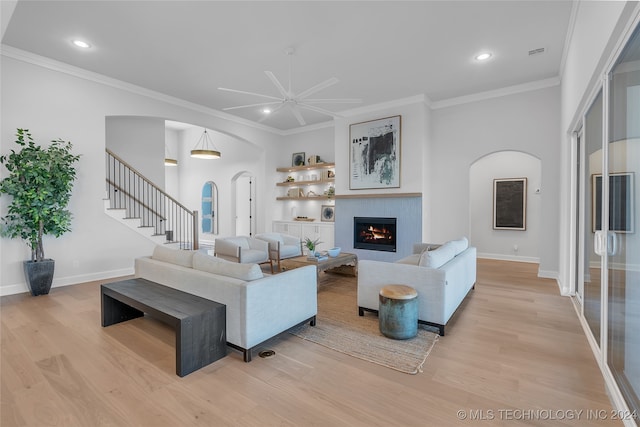 living room featuring ornamental molding, light hardwood / wood-style floors, and ceiling fan