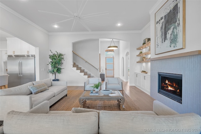 living room with light hardwood / wood-style floors, a tiled fireplace, and ornamental molding