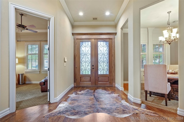 foyer with wood-type flooring, french doors, ceiling fan with notable chandelier, and crown molding