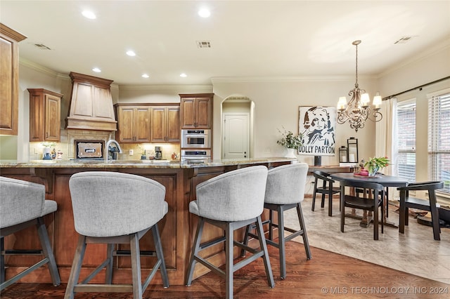 kitchen featuring light stone countertops, dark hardwood / wood-style floors, a chandelier, and crown molding