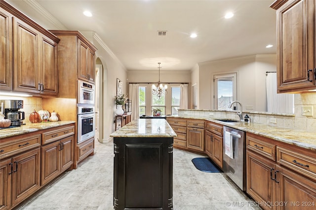 kitchen with a center island, sink, ornamental molding, light stone countertops, and appliances with stainless steel finishes