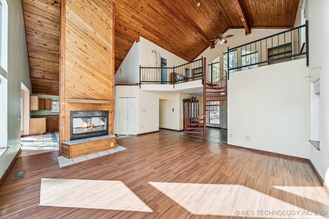 unfurnished living room featuring wood ceiling, hardwood / wood-style floors, high vaulted ceiling, a multi sided fireplace, and beam ceiling