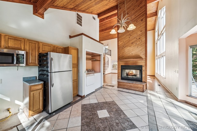 kitchen with stainless steel appliances, light tile patterned floors, washing machine and clothes dryer, and high vaulted ceiling