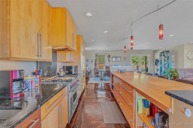 kitchen featuring tasteful backsplash, dark stone counters, dark tile patterned flooring, high end stainless steel range oven, and french doors