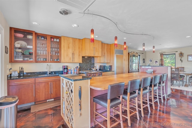 kitchen featuring dark tile patterned flooring, hanging light fixtures, decorative backsplash, sink, and a center island