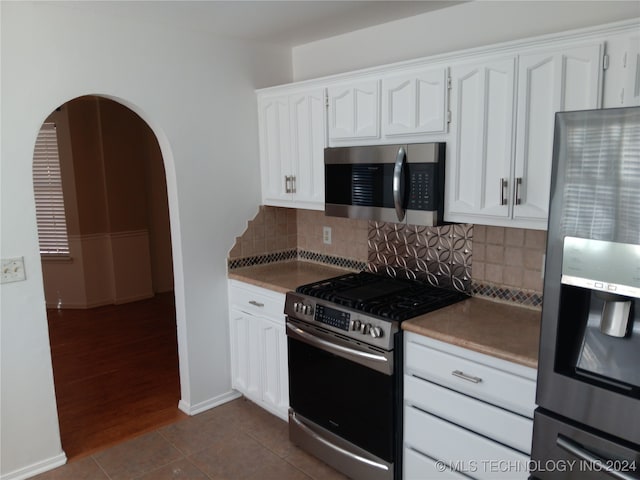 kitchen featuring dark hardwood / wood-style flooring, tasteful backsplash, white cabinetry, and appliances with stainless steel finishes