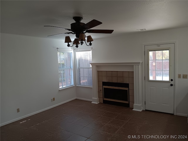 unfurnished living room with dark tile patterned flooring, ceiling fan, and a fireplace