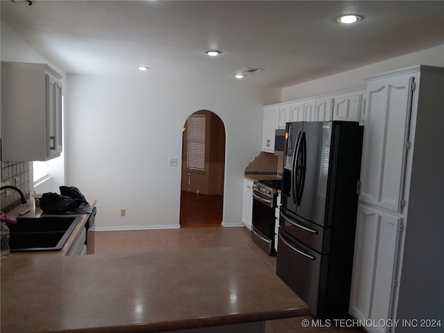 kitchen featuring sink, stainless steel range with gas cooktop, light tile patterned flooring, white cabinetry, and black refrigerator with ice dispenser