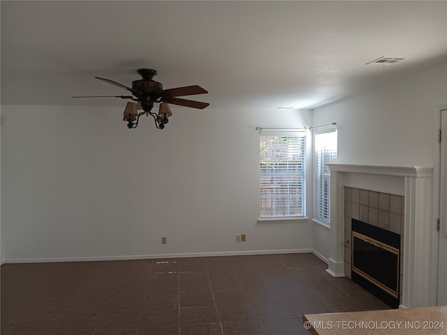 unfurnished living room with ceiling fan and a tiled fireplace