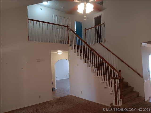 stairway featuring a high ceiling, carpet flooring, and ceiling fan