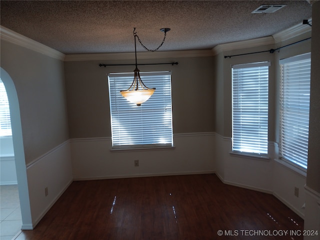 unfurnished dining area featuring hardwood / wood-style floors, a textured ceiling, and ornamental molding