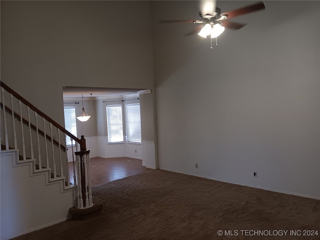 unfurnished living room with a high ceiling, carpet flooring, and ceiling fan