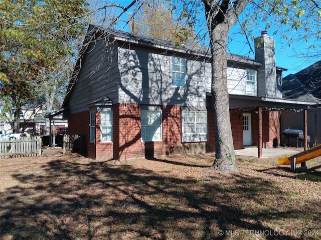 rear view of house featuring a lawn and a patio